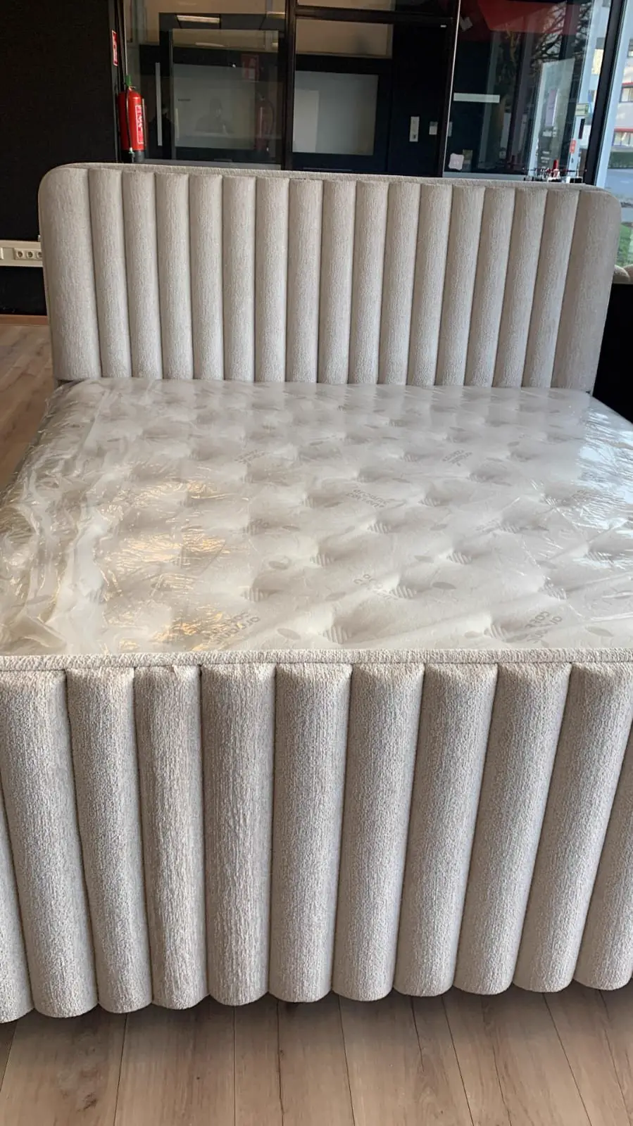 Beige boxspring met hoofdbord in verticale banen in de showroom