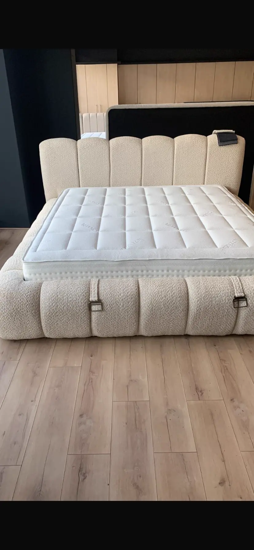 Boxspring met ivoorkleurig hoofdbord en matras in de showroom