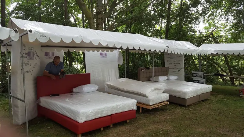 SleepOutlet market stall with box spring beds under a white tent