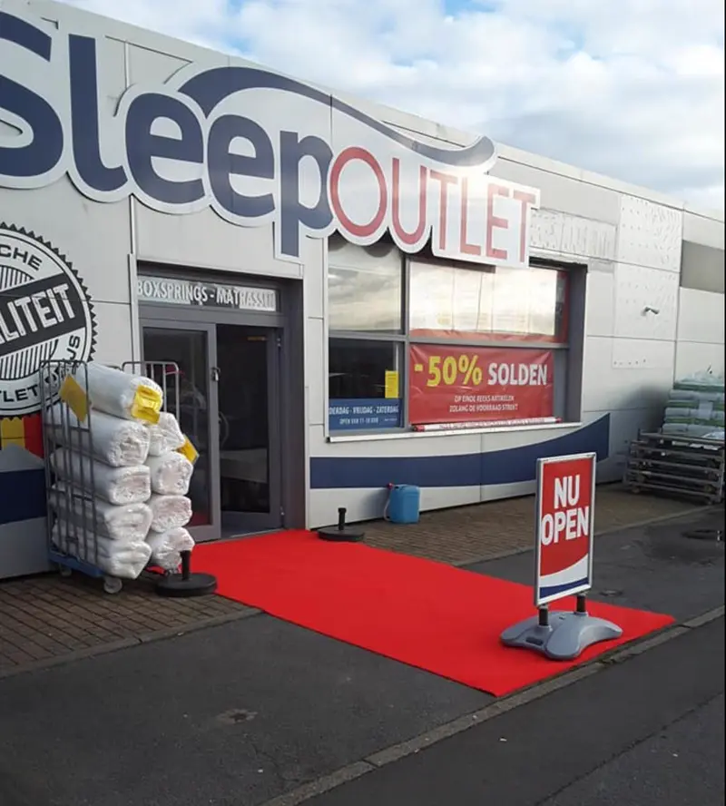 Ladenfront von SleepOutlet in Middelkerke mit großem Logo und rotem Teppich